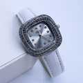 Gros plan d'une montre à quartz carrée avec lunette en diamants et bracelet en cuir blanc - Blanc Boîtier Argent