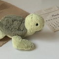Close-up of soft green plush turtle toy with textured shell next to a decorative calendar - Turtle / 28cm