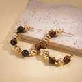 Detailed close-up of 16K gold plated tiger eye beaded hoop earrings on a beige stone slab - Gold (Real Gold Plated Silver Pin)