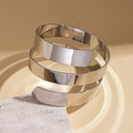 Detalle de brazalete en espiral de metal plateado pulido sobre soporte de piedra - Plateado