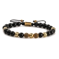 Bracelet tissé main avec perles d'onyx noires et breloques dorées sur fond blanc neutre - Bracelet en pierre noire brillante