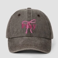 Close-up of the washed dark brown baseball cap featuring a pink bow and Pray print - One Size / Coffee