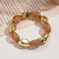 Detalle de pulsera bohemia de acrílico con cuentas doradas y ámbar con purpurina - Café Claro