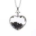 Detail view of heart-shaped glass pendant filled with black natural crushed stones - Silver + Obsidian