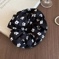 Nahaufnahme des schwarzen Seidenhaargummis mit Blumenmuster auf Vintage-Holztisch - Scrunchie / Schwarz Blumig
