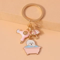 Close-up of golden keychain with enamel charms of a dog in a bathtub and a hair dryer - Hairdryer Umbrella Dog