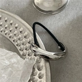 Detail von silberner Metall-Pferdeschwanz-Manschette mit schwarzem Gummiband auf Tablett - Silber