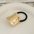 Minimalist hair tie with gold crinkled metal accent on white ceramic plate - Arched Cloud KC Gold