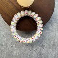 Spiral telephone cord hair tie with multi-colored polka dots on a wooden plate - Colorful Polka Dots