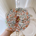 Primer plano de un coletero floral con estampados de flores naranjas y azules en tela - Pequeñas Flores Amarillas Plisadas sobre Base Beige