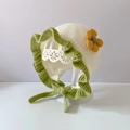 Cream knit baby hat with green lace trim and yellow flower detail on display stand - White Green Edge Flower - Lined