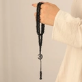 Détail du Tasbih islamique à 99 perles avec breloques étoile et lune à la main - Noir