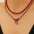 Dark red double-layered necklace featuring beaded strand and a bow pendant charm - Ancora Red Layering Style