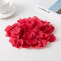 Macro shot of red non-woven artificial rose petals scattered on a white table surface - Dark Red