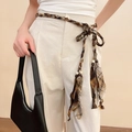 Detail of checkered woven belt with brown beads on light trousers for a retro look - Tan Plaid Braided Beaded Waist Rope
