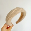 Close-up of beige plush knit headband featuring a stylish cross knot and fuzzy texture - Braided / Milk Tea