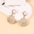 Detail of elegant gold shell drop earrings with white pearls on a minimalist background - Gold Layered Shell Pearl Dangle Earrings