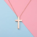 Detail of rose gold cross pendant necklace on a pink and blue split background - Rose Gold