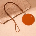 Detailopname van bruine ronde kunstlederen hanger met gevlochten koord op steen - Lederen Ronde Nekzak / Bruin