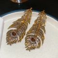 Detalle de pendientes de pluma dorados de lujo con pedrería de color ámbar y amarillo - Pin de Plata - Café - Amarillo