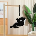 Macro-opname van een orka pluche hanger aan een houten standaard met zachte verlichting - Orka / 18cm