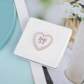Dettaglio dello specchio da borsa bianco in pelle PU con cuore di perle e fiocco d'oro - Bianco