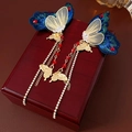 Detail van vintage gouden en blauwe vlinder oorbellen met lange kwastjes en zirkoon - Goud-Blauw-Rood (925 Zilveren Pin)