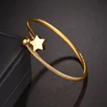Eleganter goldener Titanstahl-Armreif mit Stern- und Kugelanhänger auf dunklem Hintergrund - Fünfzackiger Stern / Glänzend