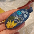 Primer plano de pasador de resina azul con flores secas naturales y hojas verdes - Azul