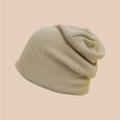 Close-up of khaki knitted slouchy beanie showing fine texture and ribbed roll-up edge details - Beige