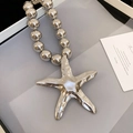 Macro view of metallic starfish pendant with irregular hammered texture on beaded chain - Silver Starfish Ball Bead Necklace