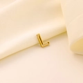 Vue macro d'un pendentif lettre L dorée sur tissu beige pour bijoux personnalisés - Lettre évidée L