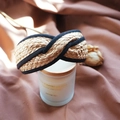 Detail of woven raffia headband with black fabric trim on a decorative candle - Natural Knotted Cross Style