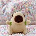 Cute plush capybara keychain with green strap sitting in colorful foam balls - Turtle Backpack Light Brown + Bead Chain