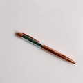 Detail view of rose gold ballpoint pen with green crystal gravel stones in transparent top - Malachite