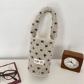 Close-up of plush white drink carrier bag with blue heart patterns and soft wool texture - Rice Blue (Blue Hearts)