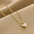 Collar de corazón dorado con incrustación de nácar sobre fondo de tela beige - Collar de Oro