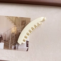 Dettaglio di un fermaglio per capelli a banana in resina opaca crema su sfondo neutro - Bianco Sporco
