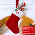Red knit Christmas stocking with letter B embroidery and holly detail hanging by a fireplace - Letter B / Red