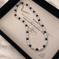 Détail du collier trèfle avec perles noires et blanches et pendentif en zircon - Collier de perles blanches