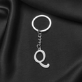 Polished silver stainless steel letter Q keychain displayed on black silk fabric - Letter Q