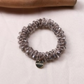 Close-up of grey faceted crystal beads and gold engraved metal charm on silk - Light Gray