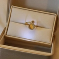 Detailed close-up of a golden zircon ring with a yellow center stone in a beige jewelry box - Gold Rotating Cat Eye Style (J0008) / Gold