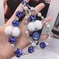 Detail of beaded phone strap with blue crystals, rhinestone balls, and white pom-poms - Blue White Rhinestone