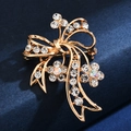 Elegant gold flower and bow brooch with shimmering crystals on a deep blue surface - Rhinestone Flower Bow