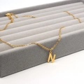 Detailed view of a gold-plated stainless steel initial N pendant necklace on a velvet tray - Letter N / Gold