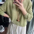 Detail of creative croissant pendant necklace with brown leather cord on green sweater - Coffee Croissant Style