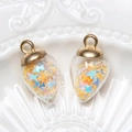 Close-up of glass light bulb pendants filled with colorful star sequins on ceramic - Water Drop / Yellow