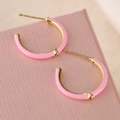 Detail von rosa emaillierten C-förmigen Goldohrringen mit kleinem Diamant am Ende - Rosa