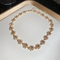 Macro detail of gold flower necklace with pink crystal centers and sparkling diamonds - Necklace - Gold - Pink